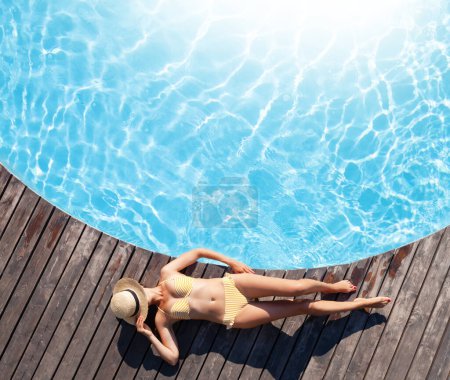 Foto de Mujer en cubierta de madera cerca de la piscina. Vacaciones de verano - Imagen libre de derechos