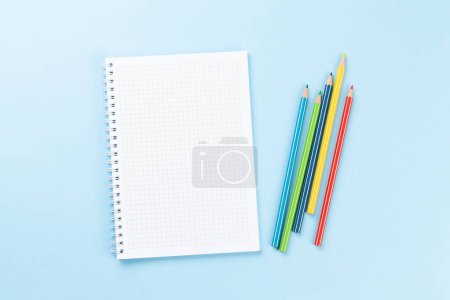 Téléchargez les photos : Bloc-notes vierge et crayons colorés. Pose plate sur fond bleu avec espace de copie - en image libre de droit