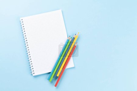 Foto de Bloc de notas en blanco y lápices de colores. Piso sobre fondo azul con espacio de copia - Imagen libre de derechos