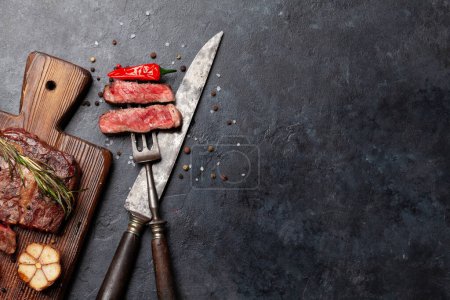 Téléchargez les photos : Tranches de steak de bœuf côtelé grillées avec des herbes et des épices. Pose plate avec espace de copie - en image libre de droit