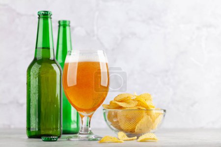 Foto de Vaso de cerveza, botellas de cerveza y papas fritas. Con espacio de copia - Imagen libre de derechos