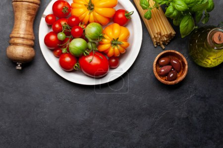 Foto de Varios tomates coloridos del jardín. Verduras frescas, aceitunas y pasta. Vista superior plano con espacio de copia - Imagen libre de derechos