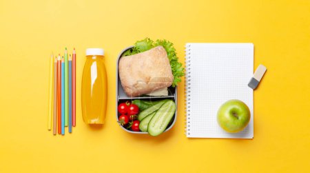 Foto de Almuerzo con sándwich, verduras y jugo. Comida y suministros escolares o de oficina. Piso con espacio de copia - Imagen libre de derechos