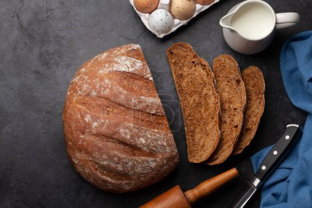 Sliced homemade bread and ingredients on stone table. Flat lay with copy space