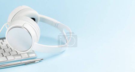 Foto de Auriculares blancos y portátil sobre fondo azul con espacio de copia. Podcast, audiolibro o plantilla de música - Imagen libre de derechos