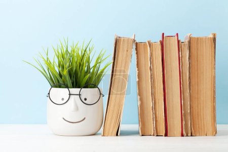 Photo for Old books and potted plant with eyeglasses. School and education template - Royalty Free Image