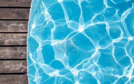 Foto de Terraza de madera junto a la piscina y agua azul de la piscina. Vista superior plano con espacio de copia - Imagen libre de derechos