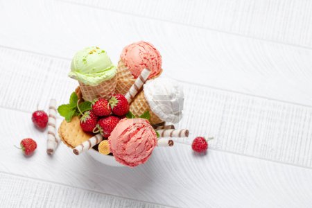 Foto de Varios helados en conos de gofre. Fresa, pistacho y helado de vainilla. Piso con espacio de copia - Imagen libre de derechos