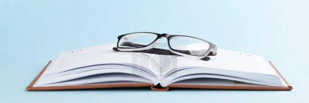 Photo for Notepad and glasses over blue background with copy space - Royalty Free Image