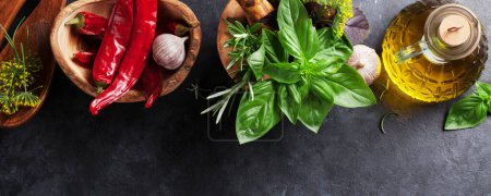 Photo for Fresh garden herbs in mortar, chili pepper and olive oil on stone table. Basil, rosemary, dill. Cooking ingredients. Flat lay - Royalty Free Image