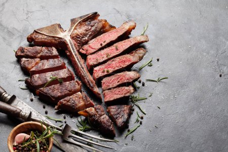 Photo for Grilled porterhouse beef steak. Sliced T-bone with herbs and spices. With copy space - Royalty Free Image