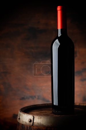 Foto de Botella de vino tinto en barrica de madera vieja. Con espacio de copia sobre fondo de madera - Imagen libre de derechos