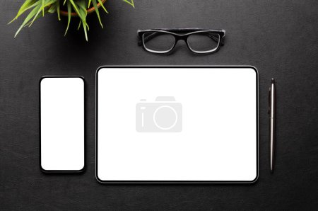 Téléchargez les photos : Tablette et smartphone avec écran blanc sur le bureau. Vue du dessus plat avec espace de copie - en image libre de droit