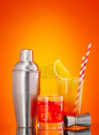 Foto de Coctelera, negroni y tequila sunrise cocktail sobre fondo naranja con espacio para copiar - Imagen libre de derechos