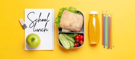 Foto de Almuerzo con sándwich, verduras y jugo. Comida y suministros escolares o de oficina. Piso con espacio de copia - Imagen libre de derechos