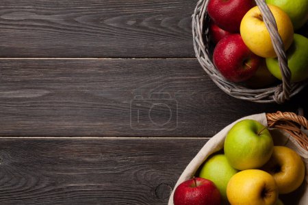 Photo for Colorful ripe apple fruits in basket on wooden table. Top view flat lay with copy space - Royalty Free Image