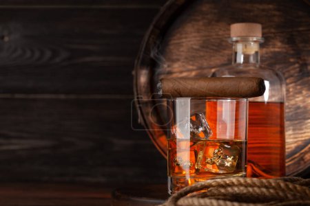 Foto de Copa y botella con coñac, whisky o ron dorado. Delante del viejo barril de madera con espacio para copias - Imagen libre de derechos