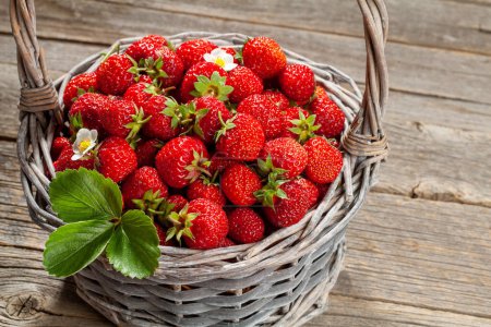 Photo for Ripe strawberries in basket on wooden table - Royalty Free Image