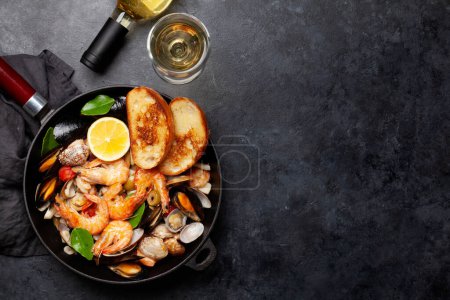 Photo for Mixed grilled seafood. Various roasted shrimps, mussels and shellfish in frying pan and white wine. Top view flat lay with copy space - Royalty Free Image