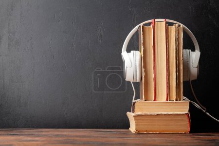 Photo for Old books and headphones on wooden table and blackboard for copy space. Audiobooks and education template - Royalty Free Image