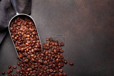 Téléchargez les photos : Grains de café torréfiés en cuillère. Pose plate sur table en pierre avec espace de copie - en image libre de droit