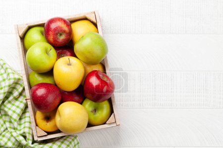 Téléchargez les photos : Fruits de pomme mûrs colorés en boîte sur une table en bois. Vue du dessus plat avec espace de copie - en image libre de droit
