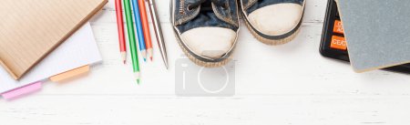 Photo for Wooden workplace backdrop with supplies and sneakers. Office and school concept. Flat lay - Royalty Free Image