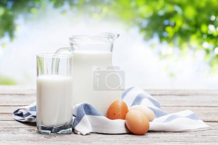 Photo for Milk in pitcher and eggs on garden wooden table. Outdoor - Royalty Free Image