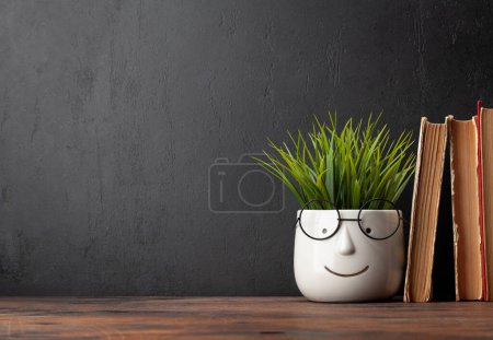 Téléchargez les photos : Livres anciens et plantes en pot avec verres sur table en bois et tableau noir pour l'espace de copie. Modèle d'école et d'éducation - en image libre de droit