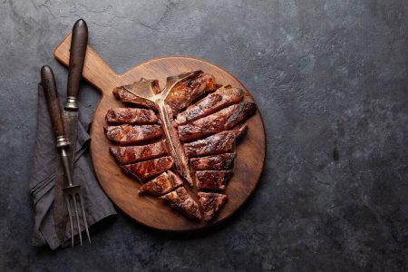 Téléchargez les photos : Steak de bœuf grillé à la porterhouse. T-bone tranché aux herbes et aux épices. Vue du dessus plat avec espace de copie - en image libre de droit