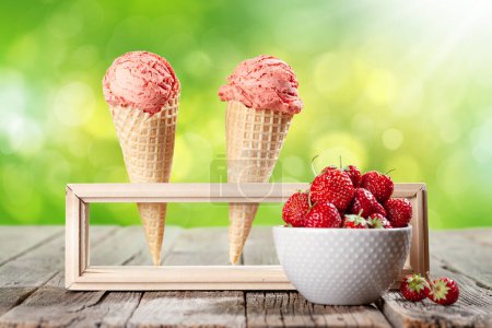Photo for Strawberry ice cream in waffle cones and bowl with berries on garden table - Royalty Free Image