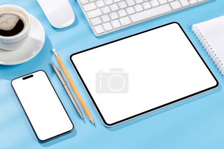 Foto de Tableta y smartphone con pantalla en blanco en el escritorio de la oficina de negocios. Espacio de trabajo con luz soleada y espacio de copia - Imagen libre de derechos