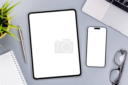 Foto de Tableta y smartphone con pantalla en blanco en el escritorio de la oficina de negocios. Espacio de trabajo plano con luz soleada y espacio de copia - Imagen libre de derechos