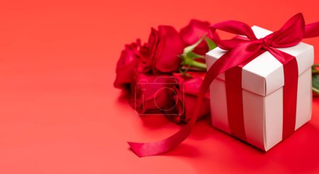 Photo for Valentines day card with gift box and rose flowers. On red background with space for your greetings - Royalty Free Image