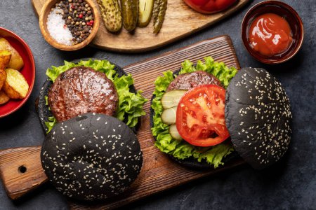 Photo for Homemade beef burgers with black buns and french fries. Flat lay - Royalty Free Image