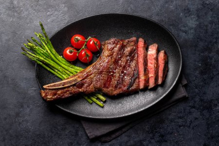 Photo for Medium rare grilled Tomahawk beef steak with asparagus. Flat lay - Royalty Free Image