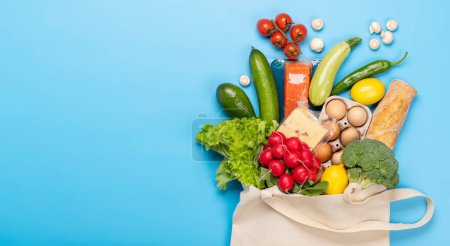 Photo for Shopping bag full of healthy food on blue background. Flat lay with copy space - Royalty Free Image