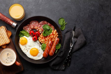 Foto de Desayuno inglés con huevos fritos, frijoles, tocino y salchichas. Vista superior plano con espacio de copia - Imagen libre de derechos