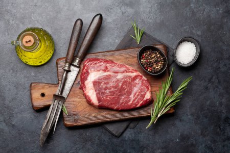 Photo for Raw ribeye steak on cutting board. Barbecue cooking. Flat lay - Royalty Free Image