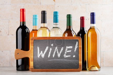 Photo for Various wine bottles on stone table. With chalkboard with wine text - Royalty Free Image