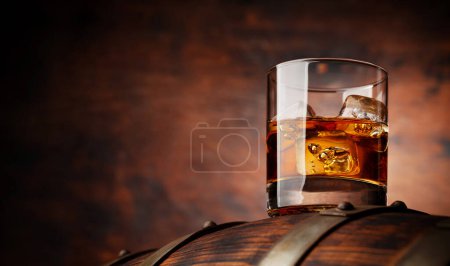 Téléchargez les photos : Un verre de whisky avec des glaçons sur le vieux tonneau. Avec espace de copie sur fond en bois - en image libre de droit