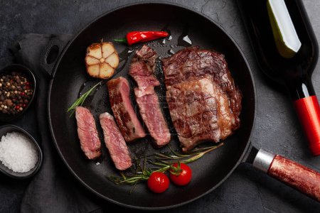 Téléchargez les photos : Steak de bœuf côtelé grillé dans une poêle avec des herbes et des épices. Pose plate - en image libre de droit