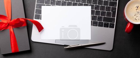 Téléchargez les photos : Gift box and laptop on office desk table. Top view flat lay with blank greeting card for your greetings. Valentines day - en image libre de droit