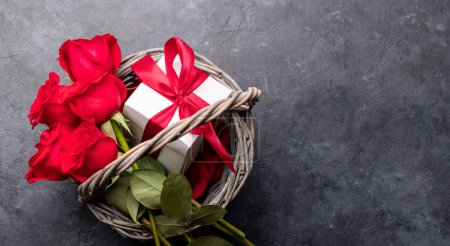 Foto de Tarjeta de San Valentín con caja de regalo y flores rosas en cesta. Sobre fondo de piedra con espacio para tus saludos - Imagen libre de derechos