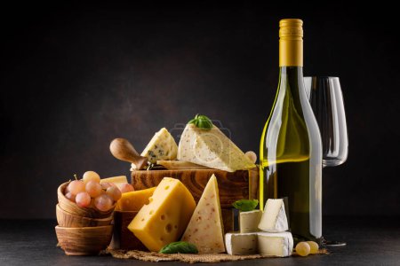 Photo for Various cheese on board and white wine. Over dark background with copy space - Royalty Free Image
