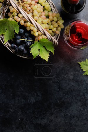 Foto de Copas de vino, botellas y uvas en cesta. Piso con espacio de copia - Imagen libre de derechos
