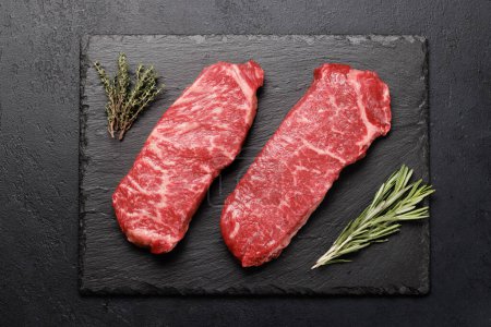 Téléchargez les photos : Prime marbled beef steaks and spices. Raw striploin steak. Flat lay - en image libre de droit