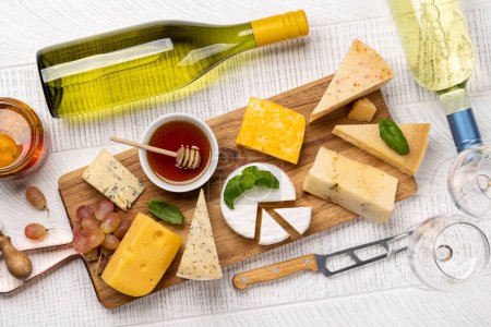 Téléchargez les photos : Various cheese on board and white wine. Flat lay - en image libre de droit