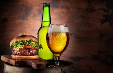 Photo for Draft beer glass, bottle and hamburger on wooden barrel. With copy space - Royalty Free Image