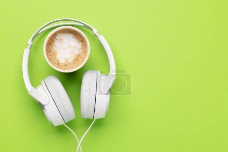 Foto de Headphones and cup of coffee on green background. Flat lay with copy space - Imagen libre de derechos